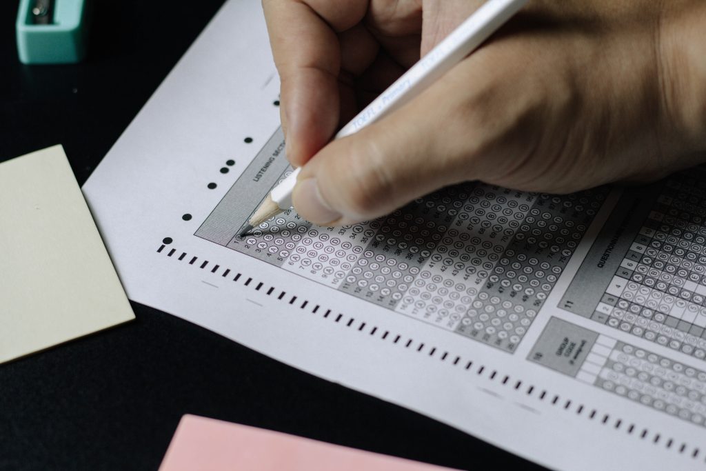 Detalle de mano realizando examen. Portada de artículo sobre test de intereses profesionales.